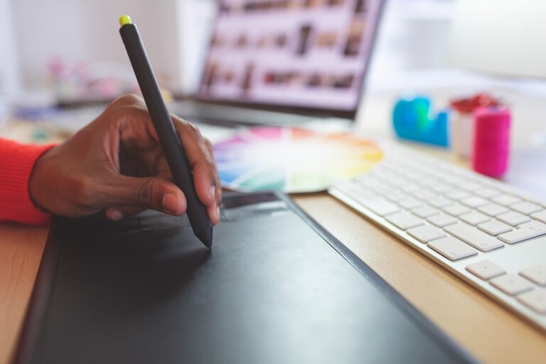 a hand holding a pen on a tablet